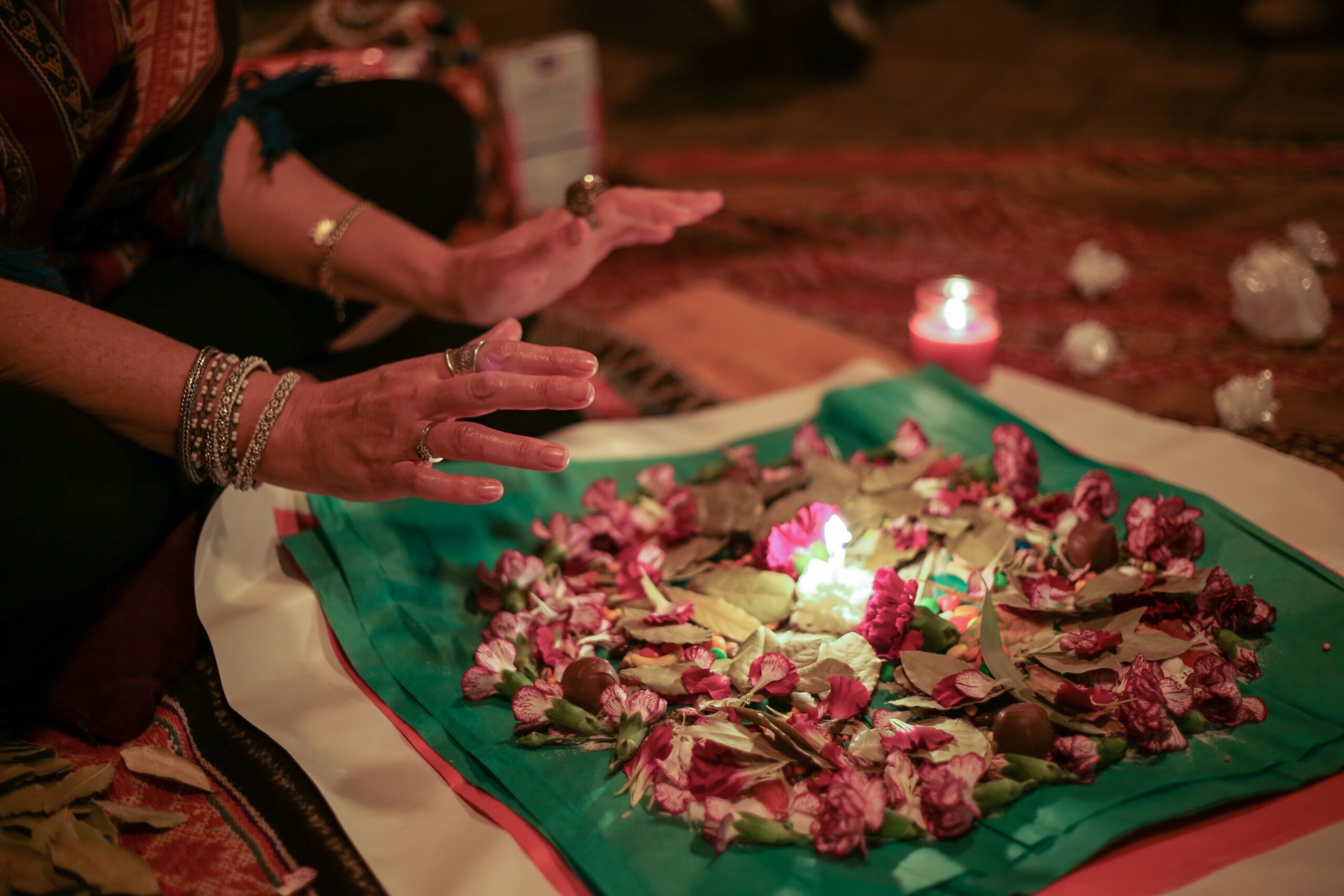 A woman placing her hand over a lit candle, preparing for a Flower Moon ritual, embracing its energy of growth, renewal, and spiritual transformation.